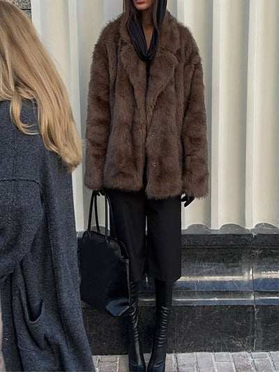 Dirbtinės odos paltas su polo apykakle ir vienspalve spalva.